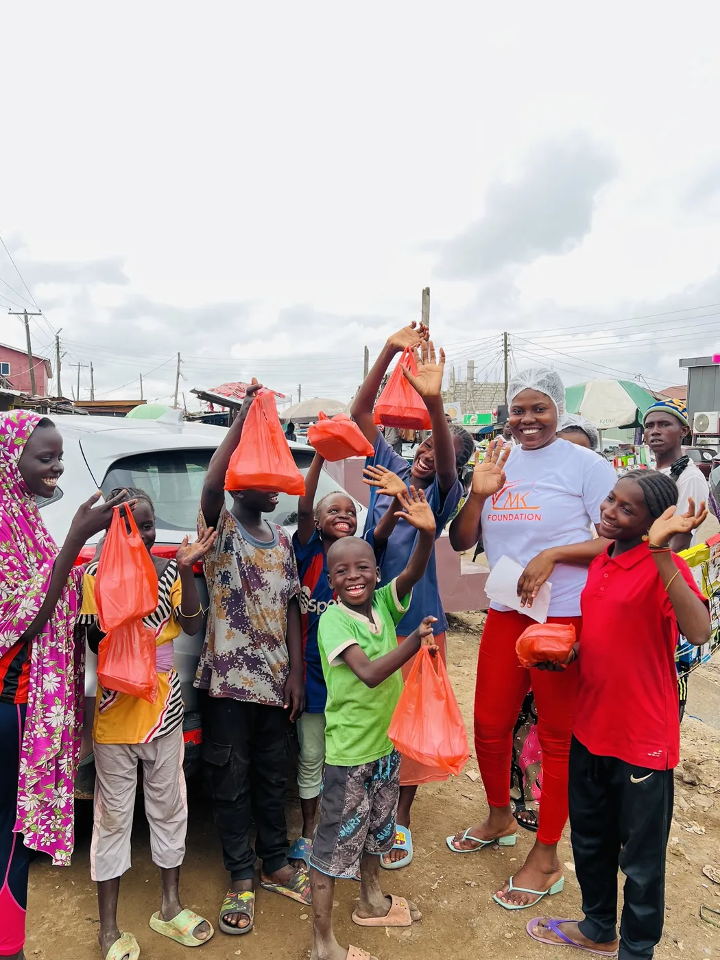 Children smiling and holding red bags of food packs