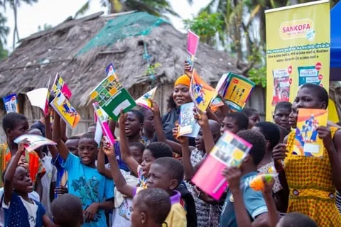 Children holding up books and items at a foundation community event