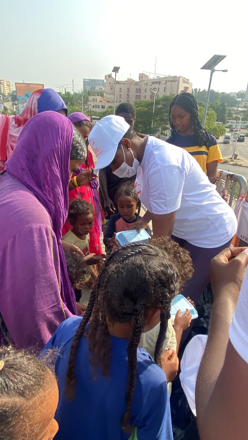 Volunteers in MK Foundation caps handing food packs to street children and women in the city