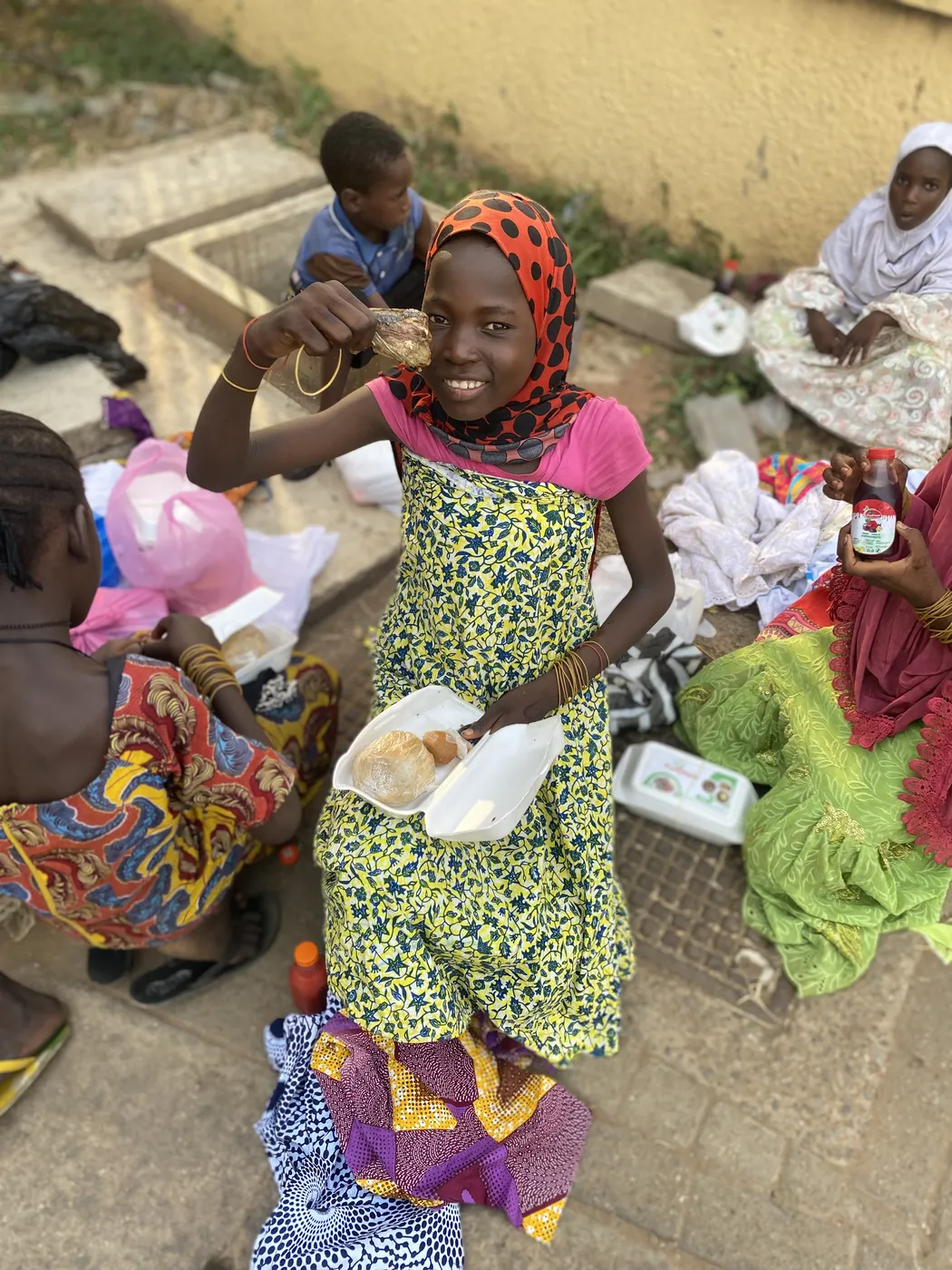 A smiling girl holding a food pack at a foundation distribution